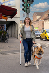 Eine Frau überquert mit Hilfe ihres Blindenführhundes eine Straße